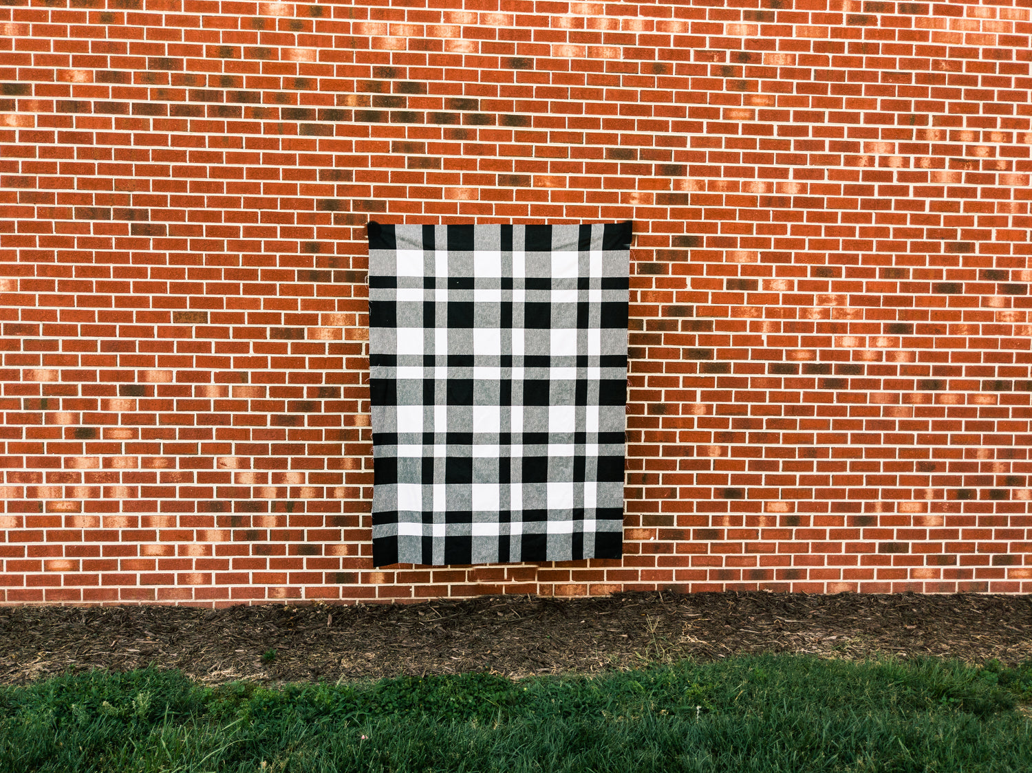 Siracusa Gingham Quilt Pattern against a brick wall